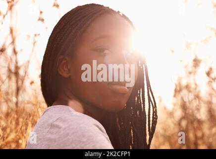 L'ora d'oro. Ritratto di una ragazza adolescente attraente in un campo con il sole dietro di lei. Foto Stock