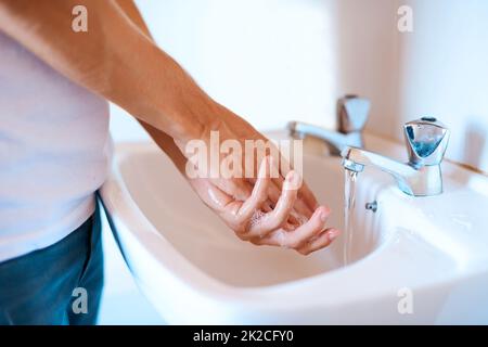 Rimani al sicuro dai germi lavando le mani regolarmente. Primo piano di un uomo irriconoscibile lavando le mani su un bacino. Foto Stock