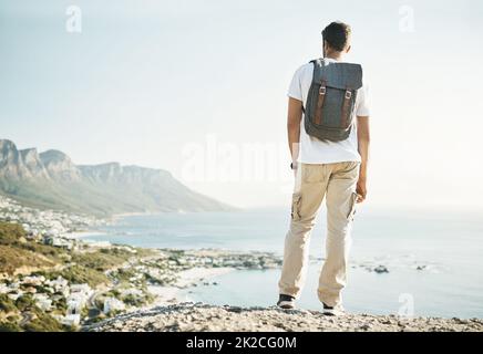 Prendendosi del tempo per ammirare la vista. Dietro l'inquadratura di un giovane uomo irriconoscibile che si affaccia sulle viste mentre si fa un'escursione in montagna. Foto Stock