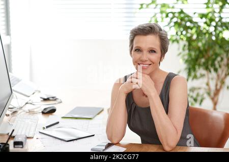 Sono orgoglioso del lavoro che faccio. Scatto di una donna matura architetto al lavoro nel suo ufficio. Foto Stock