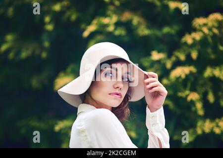 La sua bellezza è assolutamente unica nel suo genere. Ritratto di una giovane donna attraente che indossa un cappello elegante all'aperto. Foto Stock