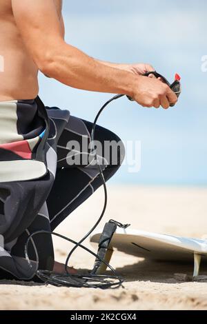 Preparatevi a navigare. Un giovane uomo in una muta che si prepara per il surf. Foto Stock