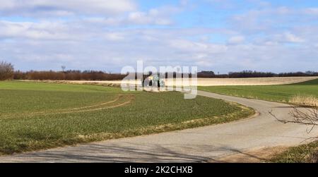 Un trattore con rimorchio grande su una strada di campagna in buone condizioni atmosferiche. Foto Stock