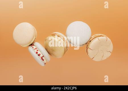 Biscotti bianchi, gialli, dorati al macaron che volano, cadono in movimento o si levitano Foto Stock