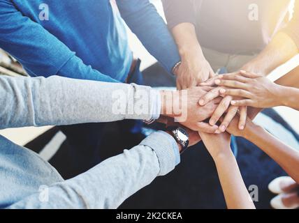 Il loro segreto è un grande lavoro di squadra. Scatto corto di un gruppo di uomini d'affari in piedi in un huddle con le loro mani accatastate. Foto Stock