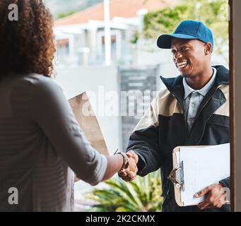 Spero che riuserete i nostri servizi. Shot di un corriere che scuote le mani con un cliente durante la consegna. Foto Stock