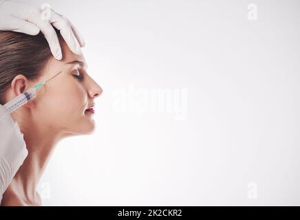 La sua arma segreta contro gli effetti del tempo. Studio girato di una giovane donna attraente che ottiene un'iniezione per scopi cosmetici. Foto Stock