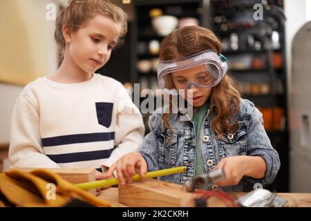 Lavora la tua giornata lontano Sparato di due bambine che fingono di essere lavoratori edili a casa. Foto Stock