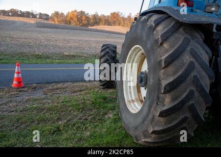 Primo piano del pneumatico blu del trattore con sfondo del campo agricolo Foto Stock