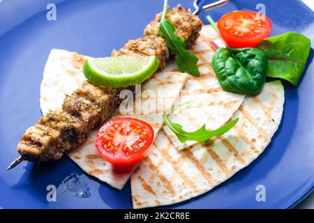 spiedino di carne alle erbe con pita pane, pomodori e lime Foto Stock