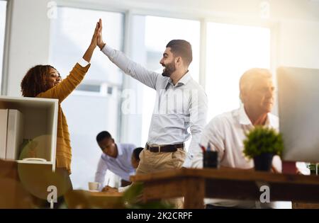 In alto. Scatto di due giovani colleghi di lavoro che si salutano a vicenda con un alto cinque mentre si è in ufficio. Foto Stock