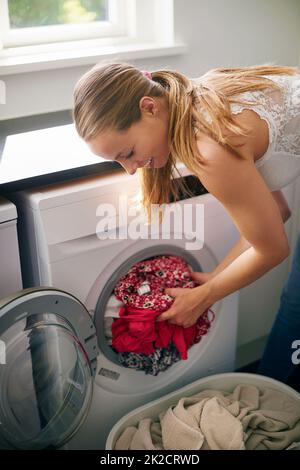 Il suo giorno di lavanderia. Scatto corto della giovane donna che fa il bucato a casa. Foto Stock