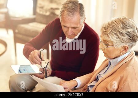 Dare un'occhiata alle loro finanze. Scatto di una coppia anziana che si forma un bilancio mentre si siede sul divano del soggiorno. Foto Stock