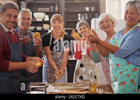 I cuochi buoni non mancano mai degli amici. Shot di un gruppo di anziani che frequentano una lezione di cucina. Foto Stock