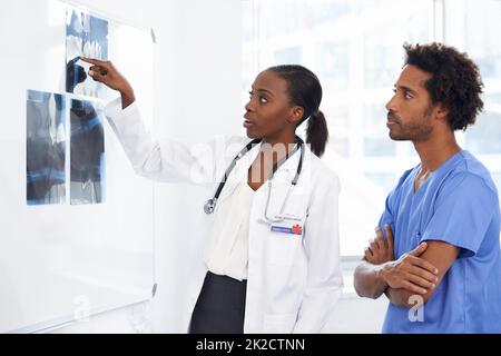 HES imparare dal meglio. Shot di un medico femminile e di un'infermiera maschile che studia i raggi X. Foto Stock