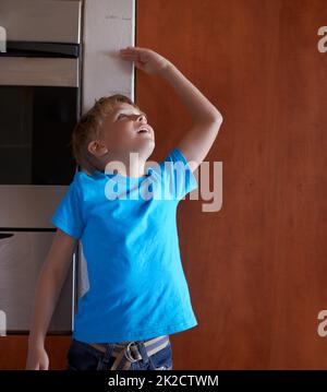 HES in rapida crescita. Un ragazzino che misura la sua altezza a casa. Foto Stock