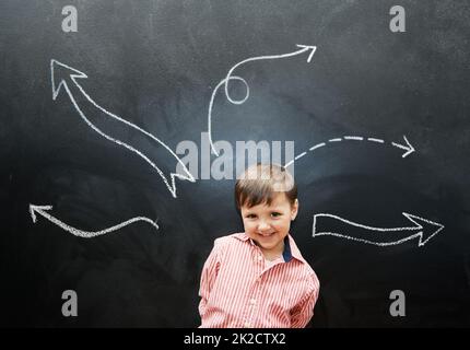 Disegnare è così divertente. Studio girato di un ragazzo adorabile con disegni in gesso dietro di lui. Foto Stock