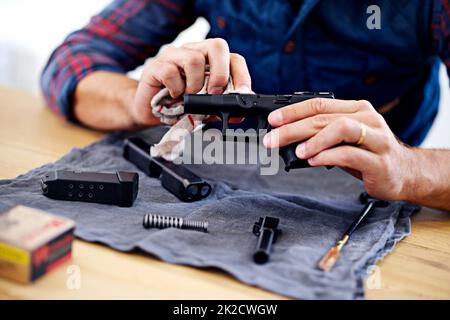 La manutenzione regolare è essenziale per ogni proprietario di pistola. Vista ritagliata di un uomo che pulisce la sua pistola. Foto Stock