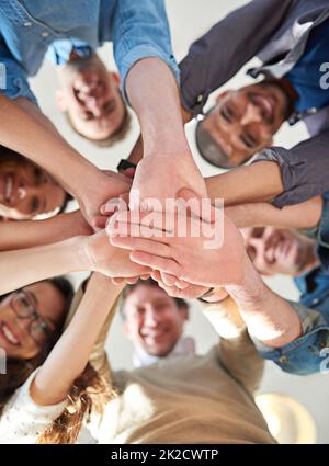 Come farlo attraverso il lavoro di squadra. Inquadratura a basso angolo di un gruppo di colleghi che si accatastano le mani l'una sull'altra. Foto Stock