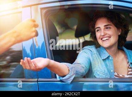 Auto nuova di zecca. La vita è buona. Scatto corto di un uomo che consegna a una giovane donna le chiavi della sua nuova auto. Foto Stock