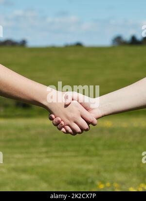 Amici fino alla fine. Scattato un colpo di due persone non identificabili che tengono le mani in piedi in un campo erboso. Foto Stock