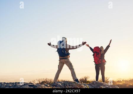 La libertà al suo meglio. Scatto di due escursionisti sulla cima di una montagna con le loro braccia sollevate godendo il panorama. Foto Stock