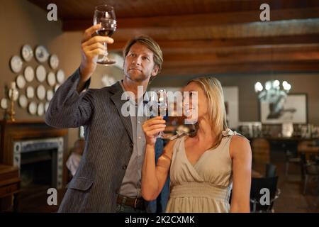 Apprezzare le cose più fini della vita.... Una coppia felice che fa una degustazione di vini in un ristorante. Foto Stock