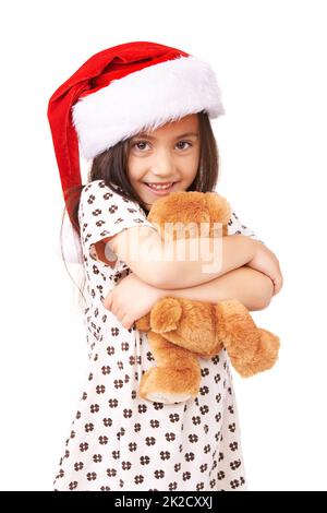 Indovina ciò che Babbo Natale mi ha dato. Un ritratto di una bambina adorabile che indossa un cappello di santa e tiene un orsacchiotto. Foto Stock