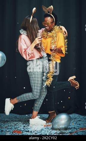 Rende la vita migliore. Scatto a tutta lunghezza di due giovani donne attraenti in piedi e abbracciarsi durante una festa di Capodanno. Foto Stock