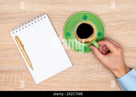 Mano con una tazza di caffè in ufficio con il notebook Foto Stock