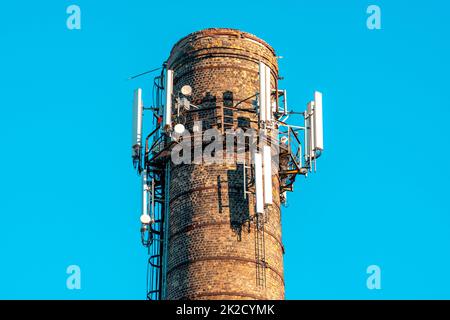 5G antenne su un tubo di mattoni contro un cielo limpido Foto Stock