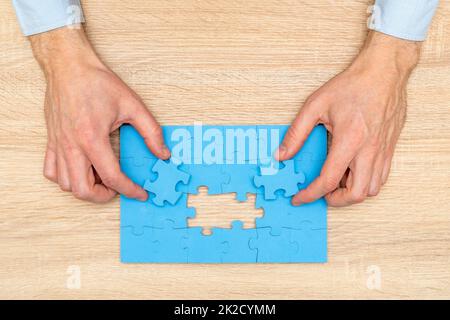 Mani di uomo d'affari mettere gli ultimi pezzi di puzzle jigsaw per completare la missione Foto Stock