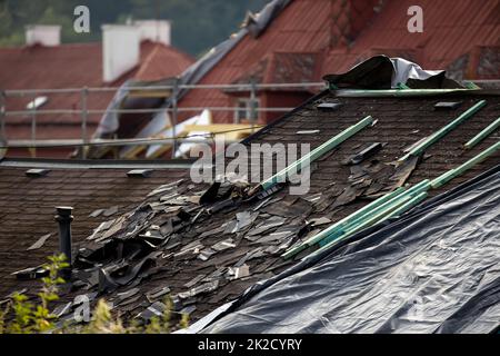 Tetto danneggiato da tempesta, tegole distrutte, danni costosi che richiedono una riparazione immediata Foto Stock