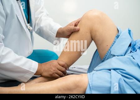 Medico asiatico fisioterapista esame, massaggio e trattamento ginocchio e gamba di paziente anziano in ospedale medico ambulatorio ortopedist infermiere. Foto Stock
