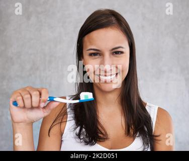 Prendersi cura dei miei bianchi perlati. Un ritratto isolato di una giovane donna che sfiorava i denti. Foto Stock