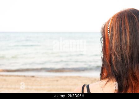 Giovane donna in piedi sulla spiaggia, guardando il mare Foto Stock