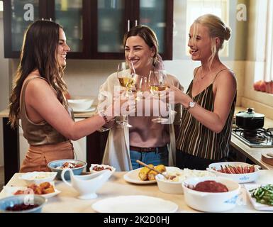 Im contento che le ragazze fanno parte della mia vita. Un breve colpo di un gruppo di giovani amici allegri che hanno un brindisi celebrativo con bevande mentre si è in piedi in cucina per preparare il cibo a casa. Foto Stock