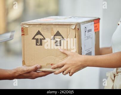 Infine il mio pacco è arrivato. Scatto di un addetto alla consegna che passa un pacco a un cliente. Foto Stock