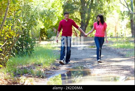 Fare una passeggiata romantica. Shot di una giovane coppia affettuosa che va per una passeggiata all'aperto. Foto Stock