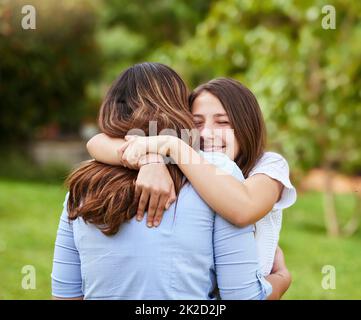 Madre e figlia amore. Shot di una giovane e allegra madre e figlia che si danno un abbraccio mentre si sta in piedi fuori in un parco durante il giorno. Foto Stock