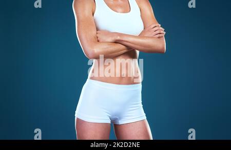 Non dia in su sui vostri obiettivi del corpo. Studio girato di una donna vestita irriconoscibile che si posa su uno sfondo blu. Foto Stock