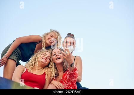 È tutto intorno all'angolo. Inquadratura ad angolo basso di un gruppo di giovani e attraenti amiche che prendono selfie in città. Foto Stock