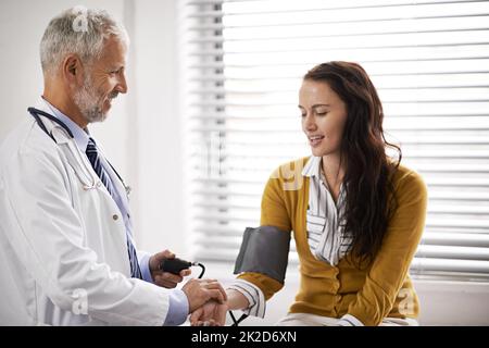 La lettura della pressione sanguigna è normale. Scatto ritagliato di un medico che controlla la pressione sanguigna di un paziente. Foto Stock