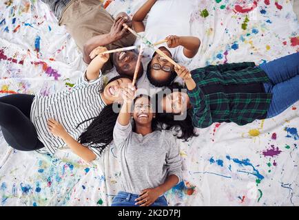 L'arte ti fa vedere il mondo in modo diverso. Foto di un gruppo di artisti che tengono insieme i loro pennelli di vernice. Foto Stock