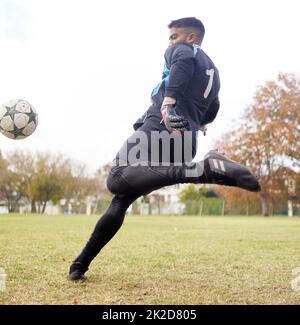 L'esercitazione non soltanto cambia il vostro corpo, esso cambia la vostra mente. Scatto di un giovane che gioca a calcio su un campo. Foto Stock