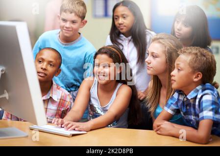 Apprendimento online collaborativo. Un gruppo di alunni che lavorano su un computer in classe. Foto Stock