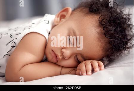 Dormi bene piccolo. Shot di un adorabile bambino che dorme tranquillamente sul letto di casa. Foto Stock