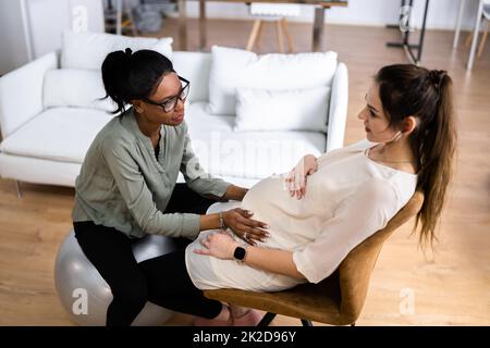 Donna incinta che ha Un massaggio da terapista femminile africano Foto Stock