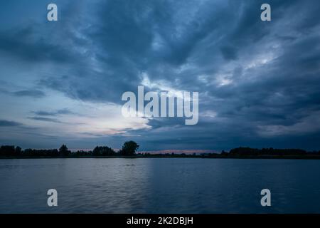 Cielo notturno nuvoloso su un lago calmo Foto Stock