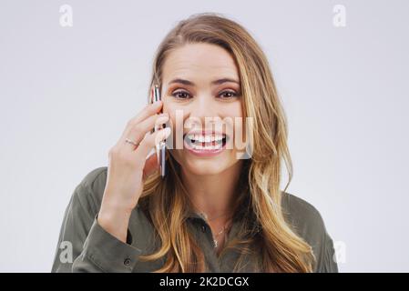 Non crederete mai a chi ha appena chiamato. Studio girato di una giovane donna utilizzando un telefono cellulare su sfondo grigio. Foto Stock